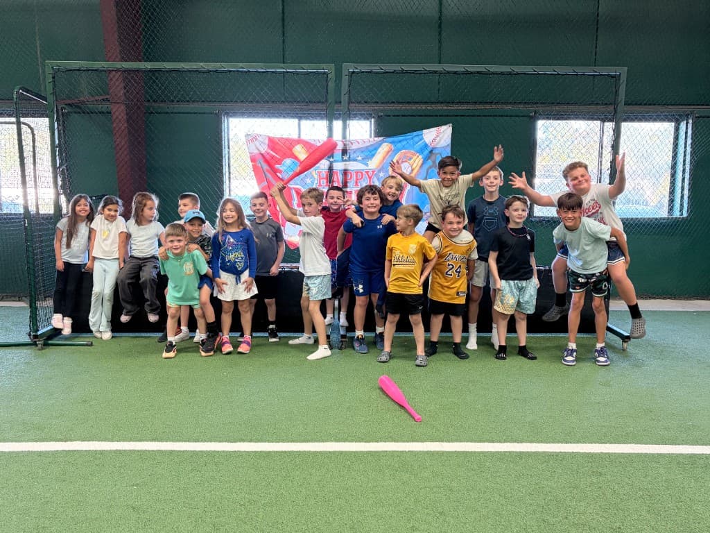 A large group of children celebrate a birthday party on the indoor turf at Sluggers.